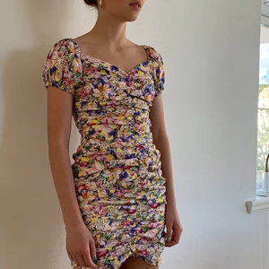 Zara sommarklänning - Zara sommarklänning i somrigt mönster. Smockad, sitter tajt och slutar på låren. Dragkedja i ryggen. Superfint skick. Använd en gång och är precis som ny. Köparen står för frakten. Fråga för fler bilder!