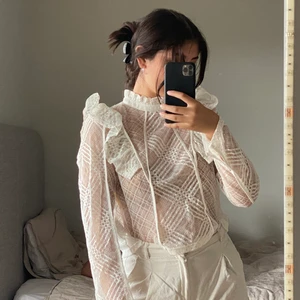 Krämvit Spetsblus med volang och slits - Fin krämvit spetsblus med volanger och slits vid ärmarna, använd ca 2 ggr. Knappar på baksidan, klippte av lappen så den inte skulle synas men gissar på 36/38, jag är en 36 iallafall. Skicka privat vid frågor osv, frakt tillkommer🤍