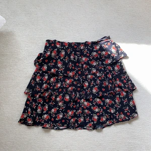 Blommig volangkjol - Röd svart blommig volangkjol med knappar där fram! Storlek 36