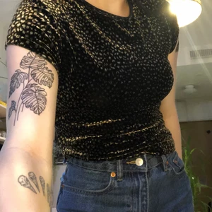 Sammet topp med leopardmönster - Top från beyond retro i sammet med mörkt leopard mönster. Man inte ser mönstret så tydligt och de ser mer ut som lite blommöster eller fläckar typ. Halsen är avklippt (de va en polokrage innan) lite stretchig