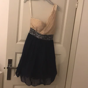 Fest klänning  - Fest klänning, med bar axel, i beige och mörkblå, den är i bra skick aldrig använd, du får med paljetter, skriv om du vill ha mer bilder❤️