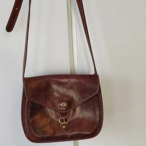 Bridge axelremsväska - Ljusbrun skinnväska, Bridge. Höjd: 18cm 23cm bred. Djup(utsida) 10cm. Dragkedjsfack. Flera fack. Fint skick.