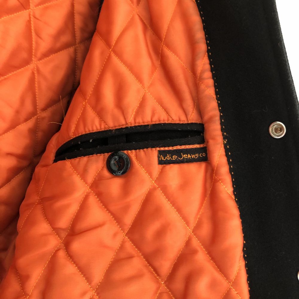 En svart lätt vadderad jacka från Nudie Jeans med gråa och orangea detaljer. Finns en 16cmx13cm innerficka på vänster sida som går att stänga med en knapp (se sista bilden). Begagnat skick. Strl S (unisex) (Om du gillar det du ser, kontakta mig så snabbt som möjligt. Gör mig av med saker som inte sålts efter ett tag.). Jackor.