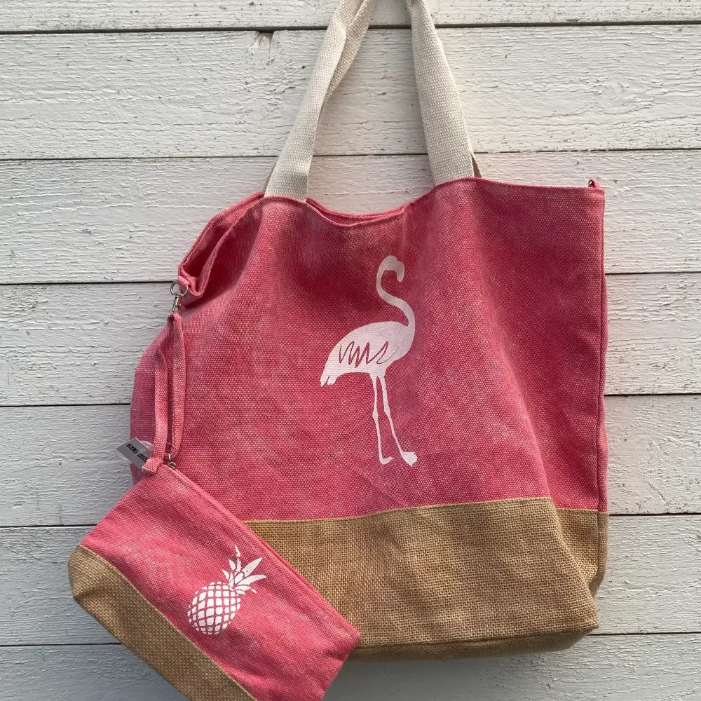 Snygg rosa/beige/krämfärgad strandväska med tillhörande necessär. Trycken är flamingo på väskan och ananas på necessären. Väskor.