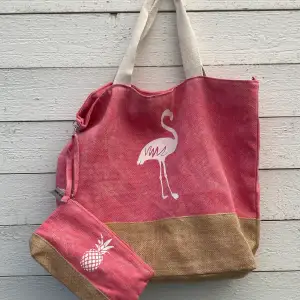 Snygg rosa/beige/krämfärgad strandväska med tillhörande necessär. Trycken är flamingo på väskan och ananas på necessären