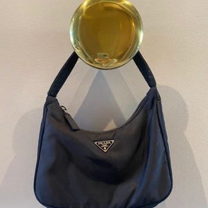 ÄKTA PRADA VÄSKA - Äkta Prada Re Edition Bag. Mycket fint skick. Tyghandtag. Mått: 22cm x 17cm x 6cm