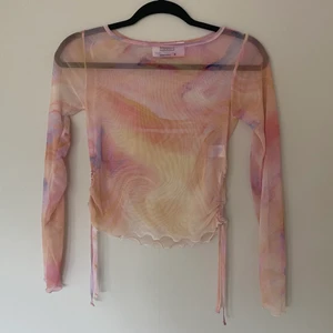 Rosa melerad meshtopp XS - Rosa melerad meshtopp med knytningar i sidan från Another Reason i oanvänt skick! Storlek UK 8 men skulle uppskatta den till en XS. Tight passform men eftersom den är mesh är den strechig.