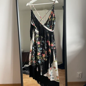 Klänning med fransdetaljer - Helt oanvänd klänning från ASOS i storlek 42 inköpt 2020 men aldrig använd. Lappen är kvar. Dragkedja i bak.