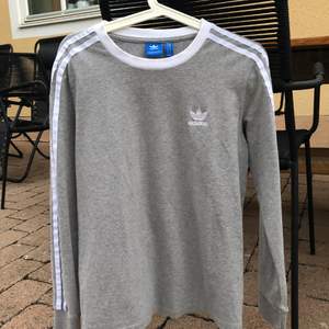 Grå långärmad tröja från Adidas med vita detaljer på ärmarna!