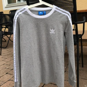 Långärmad tröja - Grå långärmad tröja från Adidas med vita detaljer på ärmarna!