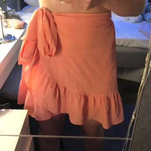 Rosa Korall kjol ifrån VeroModa - En helt oanvänd volang kjol ifrån Vero moda. Jag säljer den då den aldrig kommit till användning. Kjolen är i Strö / och är ljus korall rosa! Köparen står för frakt