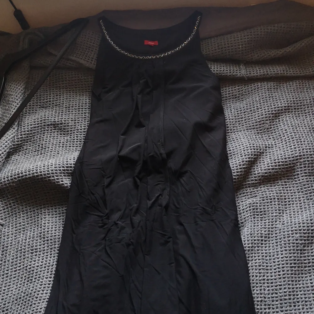 En svart enkel afton klänning med lite silver detaljer i urringningen. Använd 1 gång på en begravning och sedan hängt i garderoben sedan 3 år tillbaka. . Klänningar.