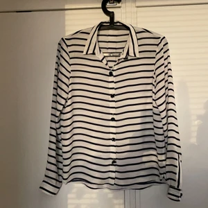 Blus skjorta från Zara - Lätt genomskinlig blus/skjorta från Zara. Vit med blå ränder och strassblommor som knappar.
