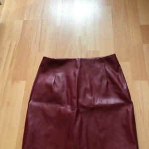 Kjol i storlek 36 ifrån Bikbok  - En kort kjol med en kedja där bak, i skinn material.