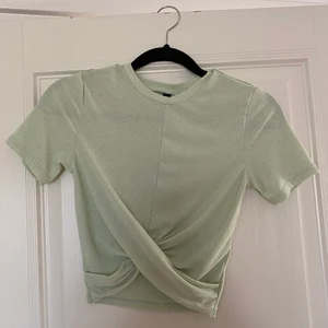 Grön snurrad topp - Jag säljer denna gröna topp i storlek XS från hm, den är använd ett fåtal gånger så den är i bra skick. Skönt material och fin detalj med det snurrade i fram! Köparen står för frakten