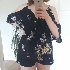 Svart rumper med blommig mönster - Svart blommig overall av polyester  med v-neck. Är i bra skick 