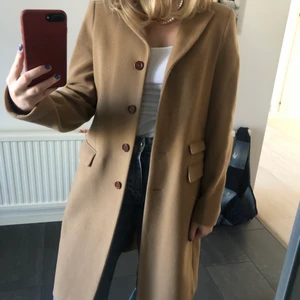 Brun kappa från NEWHOUSE storlek 34 - Säljer en jättefin brun kappa, av 75% ull, från Newhouse! Kappan är i nyskick, använd 1 gång. Kappan slutar ovanför knäna på mig som är 165cm lång! Fraktar som spårbart för 99kr. Hör av dig om du är intresserad!