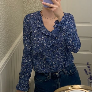 Blommig blus med volang - Säljer min fina blus, som varit en favorit. Alltid kunnat sätta på mig den här o kännt mig snygg!🥰Men nu behöver den nytt hem! Den är i väldigt fint skick, inga skador. Det står att det är strl 34 men passar även 36 (jag är 36).  Priset är exklusive frakt. Tveka inte att fråga om något. Om fler är intresserade sker budgivning i kommentarerna. 