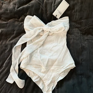 Söt vit body - OANVÄND med prislapp, men smutsig av damm därav lågt priset. Supersöt body från Bershka med rosett framtill. Rosetten är justerbar 🤍🤍 Storlek S 