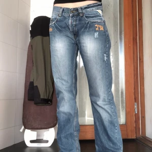 Lågmidjade jeans - Lågmidjade jeans med lite slitningar och broderingar. Sitter bra på mig som är 174cm. Midjemått: ca 86 Innerbenslängd: ca 85