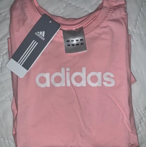 Adidas t-shirt Rosa  - Aldrig använd (lappar kvar) rosa Adidas t-shirt. Adidas loggan skimrar/glittrar. Barnstorlek L dvs 152-164 och XS för vuxen.  Säljer pga felköp.