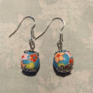 Örhängen med blommig pärla - Ett par hemmagjorda örhängen med blå pärlor och blommor. Krokarna är nickelfria, oanvända. 