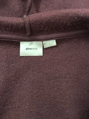 Vinröd hoodie från Gina Tricot - Säljer en vinröd hoodie från Gina Tricot i storlek S. Hoodien har dragkedja framtill, stora fickor och vita snören i huvan. Tillverkad i mjukt material och har ribbade muddar vid ärmar och midja. Perfekt för en chill och avslappnad stil.