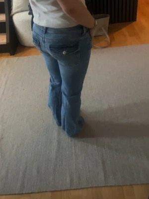 Blå low waist bootcut jeans - Snygga blå bootcut jeans med klassiska fickor och knappdetaljer bak. Jeansen har en normal passform och är tillverkade i denim med en lätt utsvängd benform. Perfekta för en avslappnad och trendig look. Stl 164, från Gina Young 