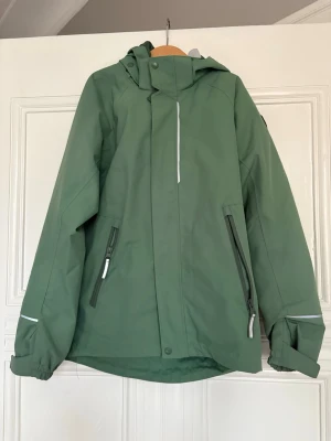 Grön barn vindjacka från Polarn O. Pyret - Snygg grön vindjacka från Polarn O.  Pyret. Elastiska muddar vid ärmsluten. Barn storlek 140, 9-10 år gammal. Nästan ny skick, säljer pga garderobsrensning. 