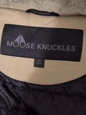  dunjacka från Moose Knuckles - Snygg  dunjacka från Moose Knuckles med quiltad design. Jackan har en klassisk passform och är perfekt för kalla dagar. Insidan har mjukt foder och yttertyget är i slitstark polyester. Stilsäker jacka för dig som vill hålla värmen.