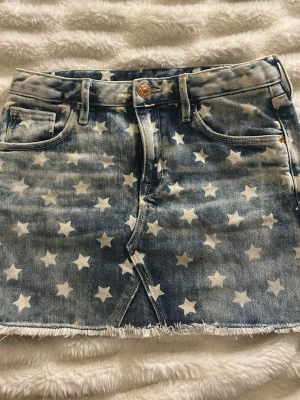 Jeanskjol med stjärnor  - Säljer en ljusblå jeanskjol med vita stjärnor över hela kjolen. Storlek XXS