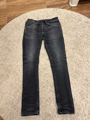 Svarta skinny jeans från dondup - Snygga svarta skinny jeans från dondup med klassiska fem fickor och diskreta slitningar. Jeansen har en smal passform och är tillverkade i mjukt denimtyg som sitter skönt hela dagen. Perfekta för dig som gillar en stilren look. Passar dig runt 170-175.