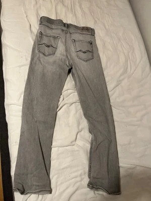 Grå replay jeans thad - Snygga grå jeans med raka ben och klassisk femficksdesign. Jeansen har kontrastsömmar och diskreta detaljer på bakfickorna. Perfekta för en avslappnad och trendig look. Tillverkade i mjukt denimtyg för skön passform.