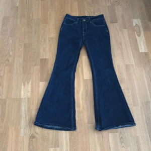 Mörkblå bootcut jeans med låg midja - Säljer ett par mörkblå bootcut jeans med låg midja. Storlek s men passar xs helt. Jeansen har klassisk femficksdesign, vida ben och kontrastsömmar. 