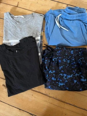 2 st T-shirts och 2 par shorts - En grå och en svart t-shirt stl 158/164 (använt skick), ett par ljusblå mjukis shorts med dragsko och ett par blåmönstrade bad shorts (knappt använda) även de i stl 158/164.100 kr för allt