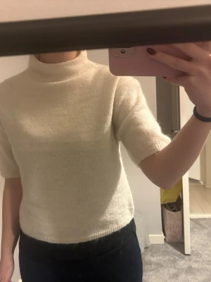 Vit stickad topp med krage och korta ärmar  - Säljer en stilren vit stickad topp med halv polokrage och korta ärmar. Tröjan har en rak passform och är gjord i ett mjukt, tunt material som känns skönt mot huden. Perfekt att matcha med jeans eller kjol för en clean look. Det står 146/152 men skulle säga att den passar XS och S. Den är helt ny utan prislapp, aldrig använt förutom när jag testade den. Tror jag köpte den för 400 men kommer inte ihåg.