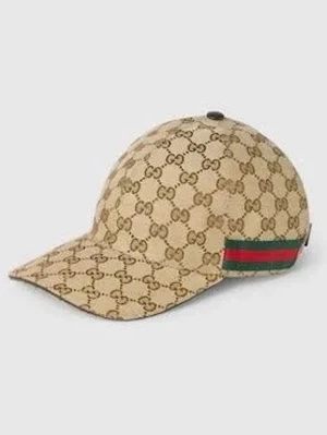 Beige keps från Gucci med GG-mönster - Säljer en beige keps från Gucci med det klassiska GG-monogrammet över hela kepsen. På sidan finns en grön och röd rand som ger en ikonisk touch. Kepsen har böjd skärm och justerbar rem bak. Perfekt för dig som vill ha en lyxig och trendig accessoar.