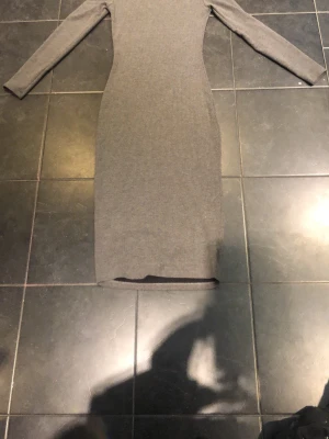 Grå ribbad långklänning Van Der Rock - Säljer en grå ribbad långklänning från Van Der Rock. Klänningen har lång ärm och en kroppsnära passform som framhäver siluetten. Perfekt för dig som gillar stilrena och enkla plagg med en modern touch.