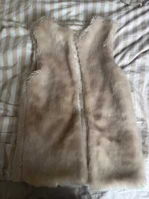 Pälsväst - Mysig pälsväst från primark. Västen har en mjuk och fluffig känsla och är perfekt att slänga över en tröja eller klänning för en trendig lager-på-lager-look.
