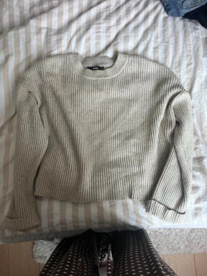 Beige ribbstickad tröja  - Säljer en beige ribbstickad tröja från BIKBOK med rund halsringning och avslappnad passform. Tröjan har långa ärmar och är tillverkad i ett mjukt, tjockare material som passar perfekt för kyligare dagar.