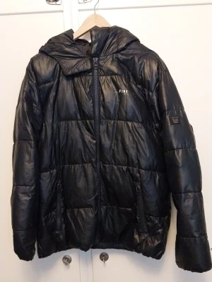 Mörk blå vinterjacka – varm & lätt, unisex modell - Säljer en mörk blå svarvadderad vinterjacka i mycket fint skick. Jackan är lätt men varm och passar perfekt för höst och vinter. Materialet är glansigt och vattenavvisande. Utrustad med huva, två dragkedjeförsedda fickor samt full dragkedja fram Märker är FIRE. Perfekt för dig som vill ha en skön och prisvärd vinterjacka.  Skickas via posten men köpare står för frakten. Vid övriga frågor skicka gärna meddelande. Lämnar självklart god omdömen om köparen gör det! Inget återköp eller retur på köpet