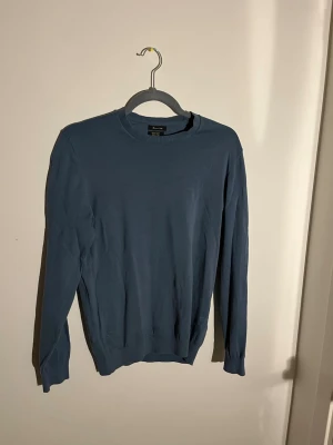 Blå bomullströja från Massimo Dutti - Snygg blå långärmad tröja från Massimo Dutti i mjuk bomull. Enkel design med rund hals och ribbade muddar vid hals, ärmslut och nederkant. Perfekt för dig som gillar stilrena och bekväma plagg.