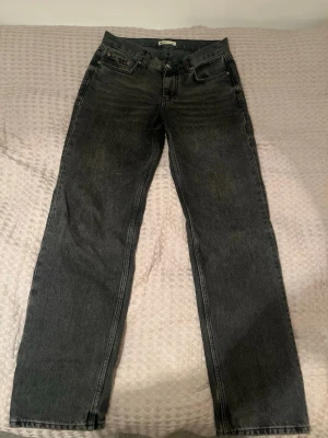 Low waist svarta jeans från Gina Tricot - Säljer ett par svarta jeans från Gina Tricot i storlek 36. Modellen har klassisk design, raka ben och normal passform. Jeansen är tillverkade i slitstarkt denim och har metallknapp och dragkedja framtill. Perfekt för dig som gillar enkel och tidlös stil.