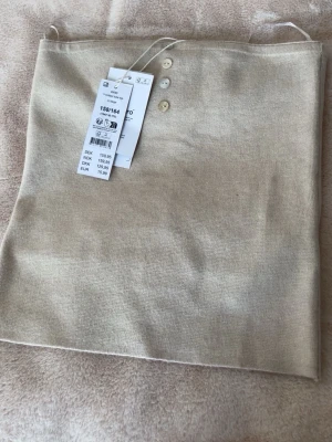 Beige stickad tubtopp med knappar - Säljer en ljusbeige stickad tubtopp från Y.F.K. i storlek 158/164. Toppen har tre dekorativa knappar framtill och är axelbandslös med en mjuk och stretchig känsla. Perfekt att styla med jeans eller kjol för en chill look. Passar mig som bär XS 