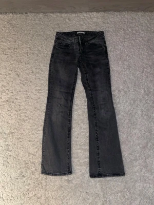 Svarta bootcut jeans från Gina tricot  - Säljer ett par svarta bootcut jeans från Gina tricot i storlek 36 petite. Passar för dig som är ca 160 cm Jeansen har klassisk femficksdesign, knapp och dragkedja fram samt snygga detaljer på bakfickorna. Materialet är jeans med en mörk tvätt och lätt slitning för en cool look.