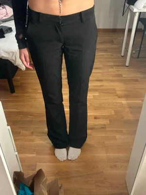 Svarta bootcut kostymbyxor BikBok - Snygga svarta kostymbyxor från BikBok i storlek 36. Byxorna har bootcut-snitt och klassisk midja med hällor för bälte. Perfekta för en clean och stilren look. Materialet känns mjukt och har en lätt stretch för extra komfort.