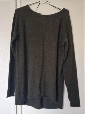 Mörkgrön finstickad långärmad tröja - Mysig mörkgrön finstickad tröja med lång ärm och enkel design. Tröjan har en rundad hals och något längre bakstycke. Perfekt att slänga på sig när det är kallt ute. Materialet är mjukt och känns skönt mot huden. Den är nopprig på både utsidan och insidan. Inga skavanker utöver det vad jag har kunnat se.