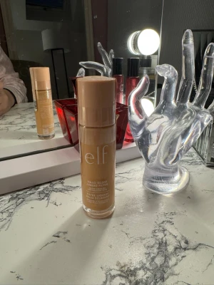 e.l.f. Halo Glow Liquid Filter 3 - Säljer en e.l.f. Halo Glow Liquid Filter i nyansen 3 Light/Medium. Flytande formula i en genomskinlig glasflaska med beige plastlock. Produkten är vegansk och cruelty free, perfekt för att ge huden en strålande glow. Passar dig som gillar naturlig lyster.