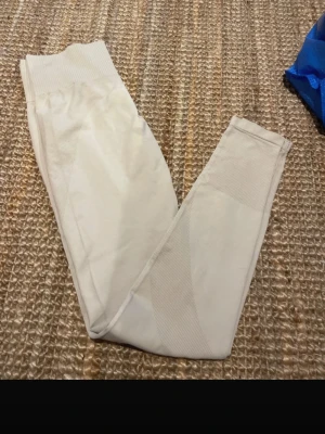 Vita seamless leggings - Snygga vita seamless leggings med hög midja och ribbade detaljer. Perfekta för träning eller chill hemma. Stretchigt material som sitter skönt och följer kroppens former. Passar dig som gillar stilrena och enkla plagg.