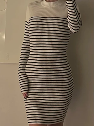 Randig ribbad stickad klänning - Säljer en snygg ribbad stickad klänning med svarta och vita horisontella ränder. Klänningen är köpt på H&M i storlek S passar även XS